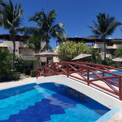 - une piscine avec un pont en bois à côté d'un bâtiment dans l'établissement Villa Sol Terrasol Acapulco Diamante, à Acapulco
