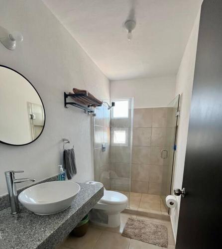 a bathroom with a sink and a toilet and a mirror at Villa Sol Terrasol Acapulco Diamante in Acapulco