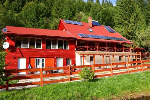 a red house with solar panels on it at Cabană în inima munților - Gálkuti Kulcsosház in Bălan