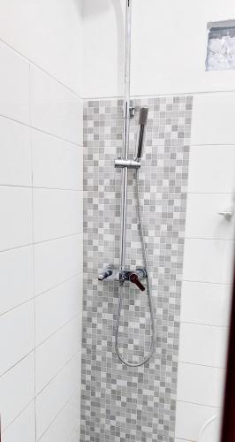 a shower with a hose on a tiled wall at Sarwi Endah Beach Cottage in Tepus