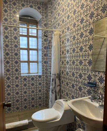 a bathroom with a toilet and a sink and a window at San Rocke House Hotel in Cuenca