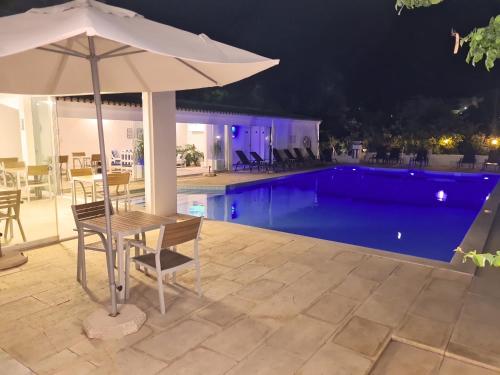 a table with an umbrella next to a swimming pool at Hotel Alcaide in Portimão
