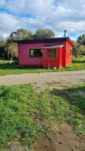 a small red and red house in a field at Tiny Cabaña para 2 personas en Llifén in llifen