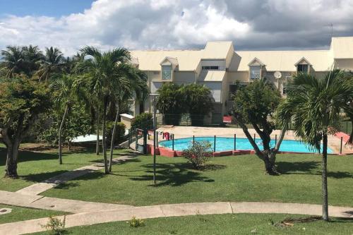 a resort with a swimming pool and palm trees at Gîte Le Gecko - Le Gosier in Saint-Félix