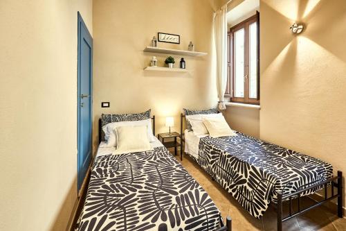 two beds in a small room with a window at La Casa di Nonna Danda in Montepulciano