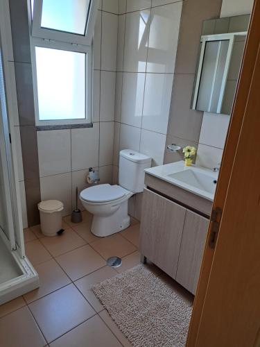 a bathroom with a toilet and a sink and a window at Hills and Atlantic Ocean retreat - Conceição House in Calheta