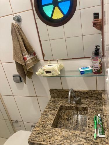 a bathroom with a sink and a clock on the wall at Família 13 in Peruíbe