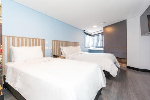two beds in a hotel room with white sheets at Terrazas in Bogotá