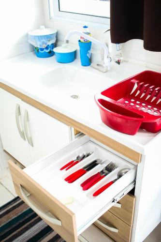 a kitchen drawer with red utensils in it at Loft05 COMPLETO AR INTERNET GARAGEM próx Aparecida e Indústrias in Pindamonhangaba