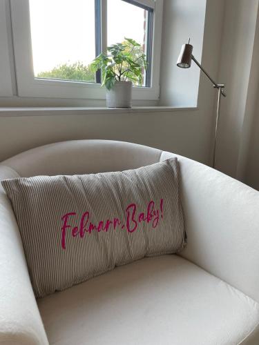 a pillow on a white couch with a window at Linnebarg Hus 3 in Bisdorf