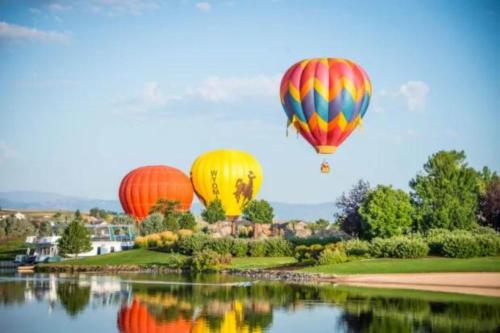 three hot air balloons flying over a body of water at Downtown Windsor Home with Hot Tub and Pool Table in Windsor