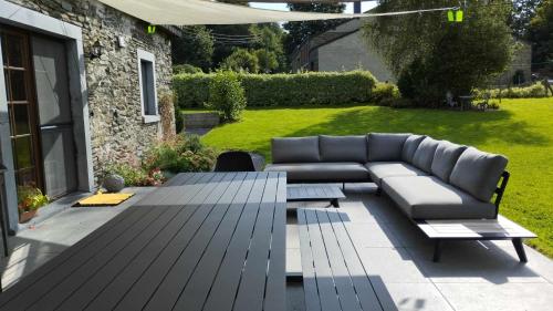 a patio with a couch and a table in a yard at Une parenthèse en Ardenne in Nollevaux