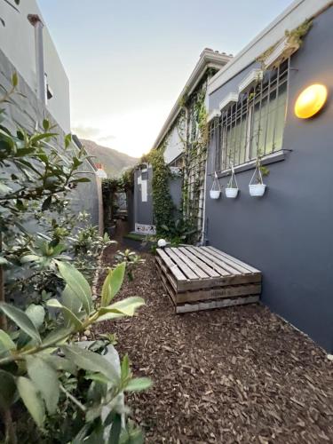 a garden with a wooden bench next to a building at Seaside Getaway @ Swallow House Suite #2 in Cape Town