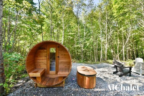 Una pequeña sauna de madera con un taburete y un tocón. en Le Scandinave - Détente avec Sauna et Spa privé, en Sainte-Catherine