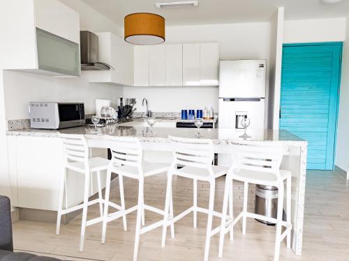 a kitchen with a white counter and white stools at Sanctuary by Playa Caracol Residences in Punta Chame
