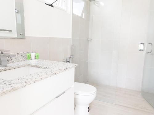 a white bathroom with a toilet and a sink at Sanctuary by Playa Caracol Residences in Punta Chame