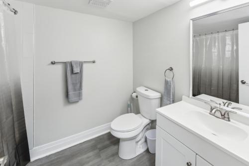 a white bathroom with a toilet and a sink at Pine Brook 416 I Corporate 15Br Apartment ! Pool in Newark
