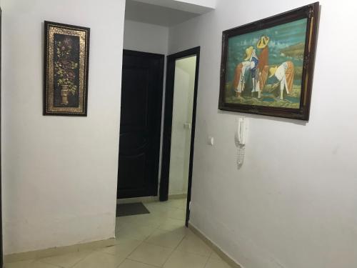 Appartement Familial Proche Aeroport Bab Andalous Tanger في طنجة: ممر به لوحة لامرأة تركب حصانًا