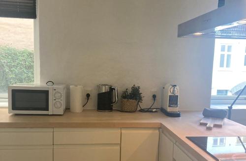 a kitchen counter with a microwave and appliances on it at Perfekt beliggenhed i centrum in Aalborg