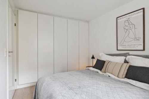 a bedroom with a large bed with white walls at Perfekt beliggenhed i centrum in Aalborg