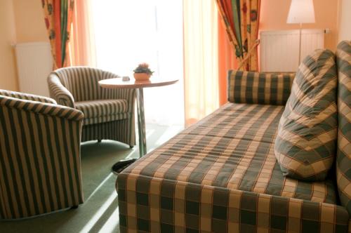 Zimmer mit 2 Stühlen, einem Sofa und einem Tisch in der Unterkunft Hotel am Waldbad in Uelsen