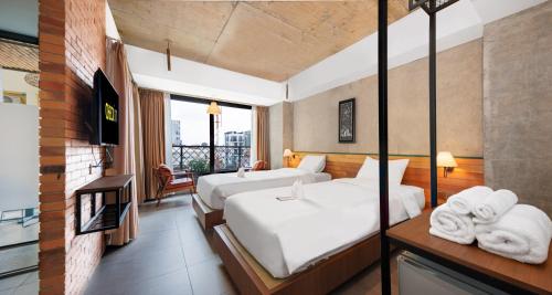 a hotel room with two beds and a balcony at CHECK inn Phnom Penh Royal Palace in Phnom Penh