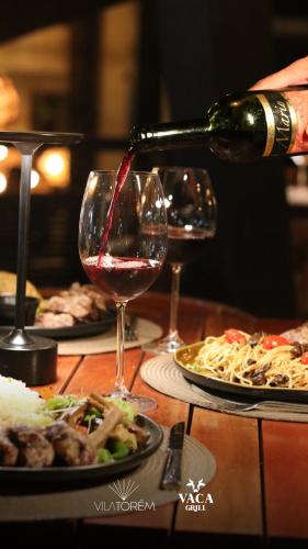 a person pouring wine into a wine glass on a table at Vila Torém in Icaraí