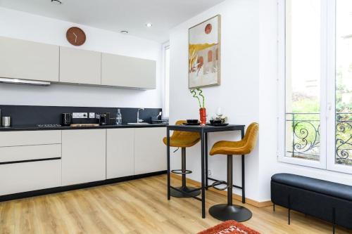 une cuisine avec des armoires blanches et une table et des chaises dans l'établissement Appartement Cosy Juvisy, à Juvisy-sur-Orge