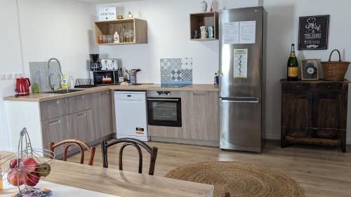 une cuisine avec un réfrigérateur en acier inoxydable et une table dans l'établissement CITADELLE - 3 chambres - 4 Lits - Centre ville - Proche Gare - WIFI - Géré par PrestaZen'Services, à Verdun-sur-Meuse