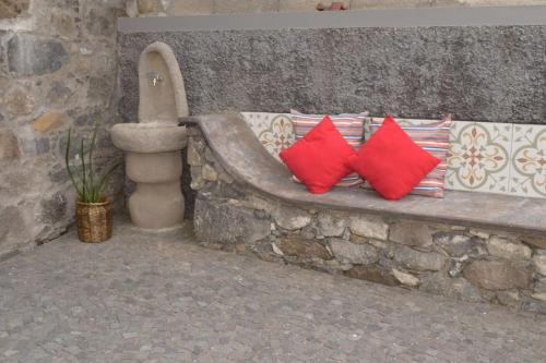 a stone bench with two red pillows on it at Sonho Paixão in São Vicente