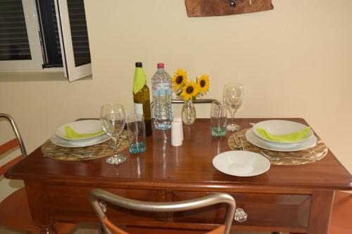 a wooden table with plates and glasses and flowers on it at Sonho Paixão in São Vicente