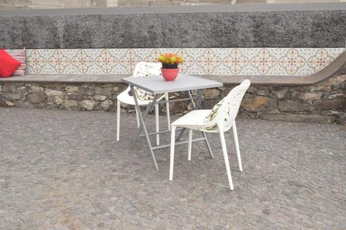 a table with two chairs and a table with a flower pot on it at Sonho Paixão in São Vicente