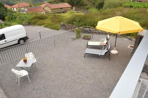 a patio with a table and a yellow umbrella at Sonho Paixão in São Vicente