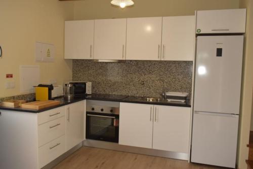 a kitchen with white cabinets and a refrigerator at Sonho Paixão in São Vicente