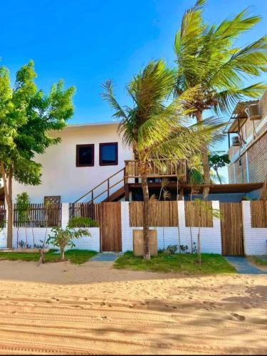 a house on the beach with a deck and palm trees at Casa Pietro 1 in Jericoacoara