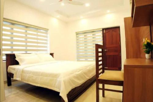 a bedroom with a bed and a chair in it at Lakeshore Premier Serviced Villa in Alleppey