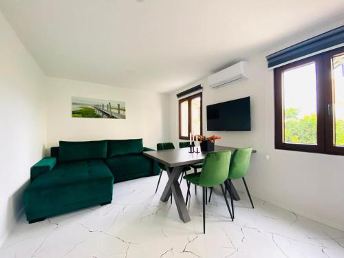 a living room with a couch and a table and green chairs at Apartment Daria in Postira