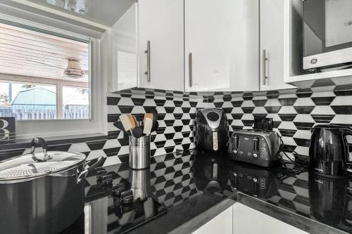 a kitchen with a black and white checkered wall at Amazing Home w Heated Pool 8 mins to the Beach in Lighthouse Point
