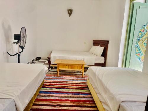 a room with two beds and a table in it at Riad Dar Lokman in Marrakech