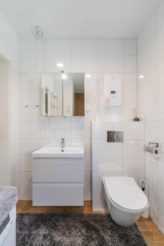 a white bathroom with a sink and a toilet at Leśna Enklawa in Zagórze