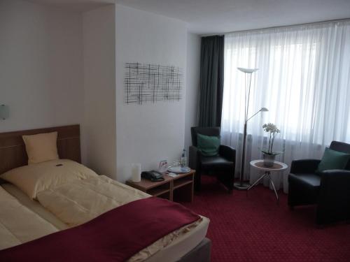a hotel room with a bed and a chair at Hotel Sechzehn in Leverkusen