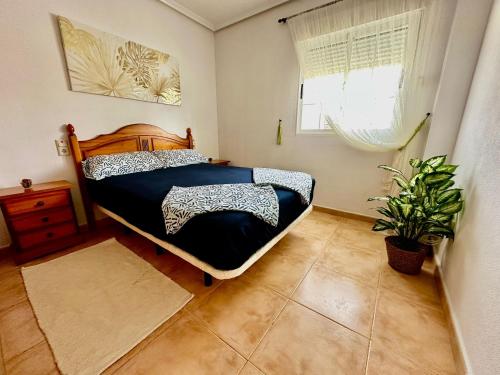 a bedroom with a bed and a plant in it at Bungalow Carabassi Mediterraneo 3 Pool and roof terrace in Puerto Marino