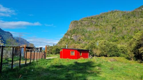 a red shed in a field with a mountain at Tiny Cabaña para 2 personas en Llifén in llifen
