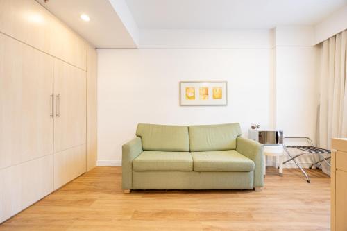 a living room with a green couch and a table at STD - Anora Spaces - Stadium Alphaville in Barueri