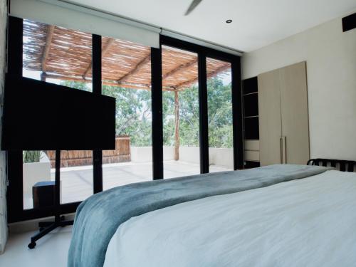 a bedroom with a large bed and large windows at Las Villas I & II in Tulum