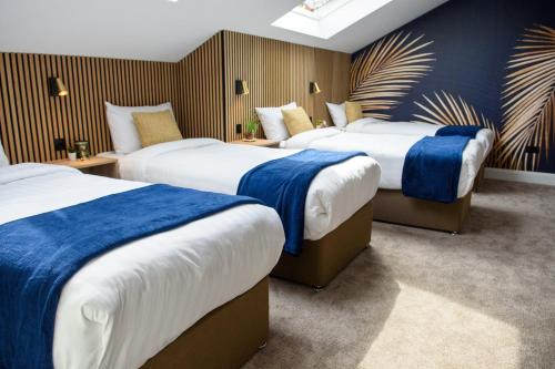 a hotel room with three beds with blue and white sheets at Rowing club house in Carrick on Shannon