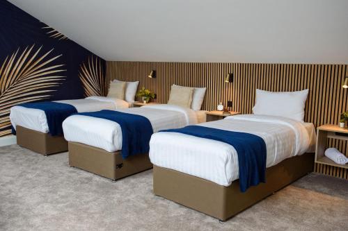 a bedroom with three beds with blue and white sheets at Rowing club house in Carrick on Shannon