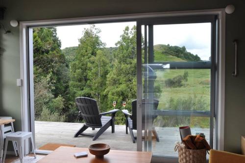 a room with a sliding glass door looking out onto a deck at The Rimu Hut - Off-grid Luxury riverside cabin in Te Anga
