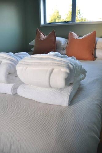 a pile of towels sitting on top of a bed at The Rimu Hut - Off-grid Luxury riverside cabin in Te Anga