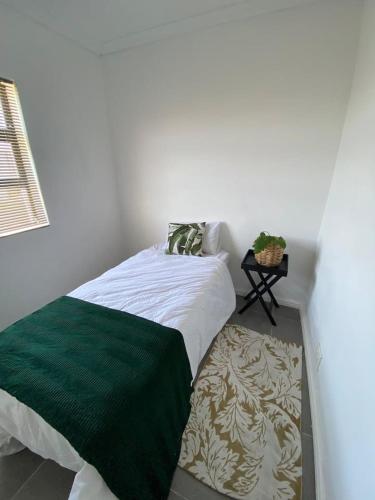 ein Schlafzimmer mit einem Bett mit einer grünen und weißen Decke in der Unterkunft Cottage on 36 Neethlingshof in Kapstadt